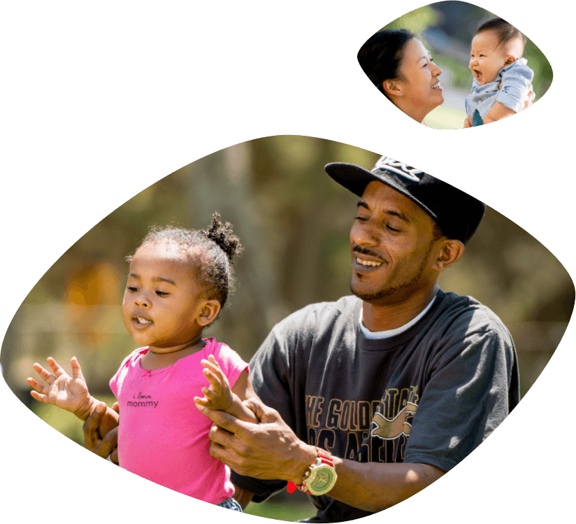 Un sonriente papá afroamericano, vestido en camiseta y gorra de béisbol, le está ayudando a su sonriente hijita a pararse.