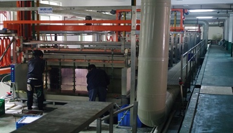 Facility with metal pipes and workers working on machinary.